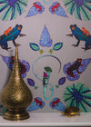 Frog wallpaper with brightly coloured frogs and leaves hung on a wall above mantlepiece